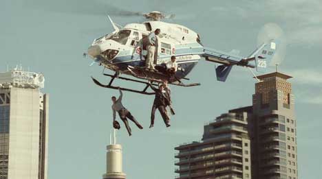 Men suspended from a helicopter over Stunt City