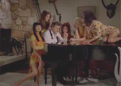 Bruce Campbell surrounded by women at the piano